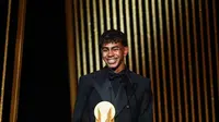 Penyerang muda Barcelona, Lamine Yamal, menerima Kopa Trophy, lambang pemenang predikat pemain muda terbaik di seremonial Ballon d'Or yang berlangsung di Theatre du Chatelet di Paris, Senin (28/10/2024) malam waktu setempat. (FRANCK FIFE / AFP)