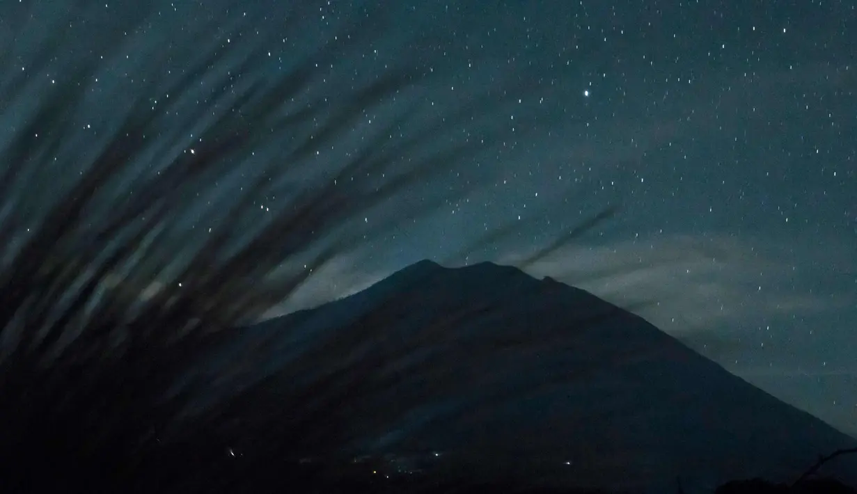 Pemandangan malam Gunung Agung di bawah langit penuh bintang terlihat dari Kubu di Karangasem, Bali, (28/9). Gunung Agung sejak sepekan lalu masih bertahan dengan status awas atau Level IV. (AFP Photo/Bay Ismoyo)