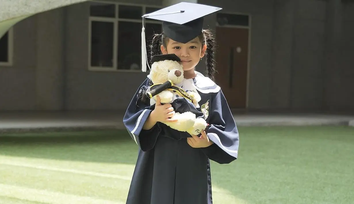 Ruben dan Sarwendah tetap kompak mendukung perjalanan pendidikan anak-anak mereka. Di momen bahagianya, Thania tampil menggemaskan dengan pakaian toga, lengkap dengan topinya. Gadis kecil berusia 5 tahun itu mendekap boneka beruang hadiah kelulusannya. (Liputan6.com/IG/@ruben_onsu)
