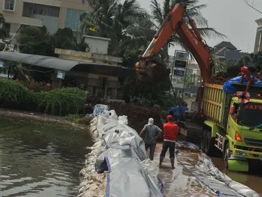 Alat berat dikerahkan untuk membuat tanggul untuk mencegah banjir di kawasan Perumahan Pantai Mutiara, Jakarta, Sabtu (4/6). Akibat tanggul jebol kawasan tersebut tergenang dengan ketinggian 50-60 sentimeter. (Liputan6.com/Gempur M Surya)