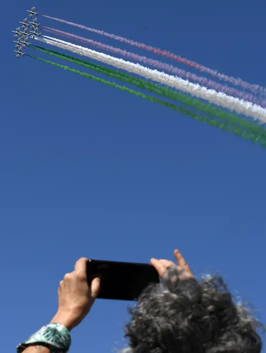 Penonton mengabadikan pertunjukan tim aerobatik Italia Frecce Tricolori dalam upacara peringatan Hari Pembebasan Italia di Roma, Italia, Sabtu (25/4/2020). Italia memperingati Hari Pembebasan ke-75 dengan cara yang paling tidak biasa karena digelar di masa pandemi virus corona COVID-19. (Xinhua)