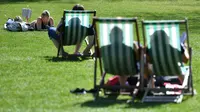 Warga Inggris bersantai sambil berjemur di sebuah taman di pusat kota London,  Inggris, Minggu (9/4). Inggris sedang mendapati musim panas di negaranya. Diperkirakan suhu akan mencapai 25 derajat Celcius. (AFP PHOTO / BEN STANSALL)