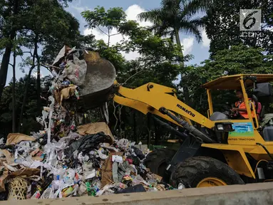 Petugas kebersihan dibantu alat berat membersihkan sampah Tahun Baru 2018 di Monas, Jakarta, Senin (1/1). Setelah perayaan malam tahun baru 2018, sampah sisa pengunjung berserakan di lokasi perayaan. (Liputan6.com/Faizal Fanani)