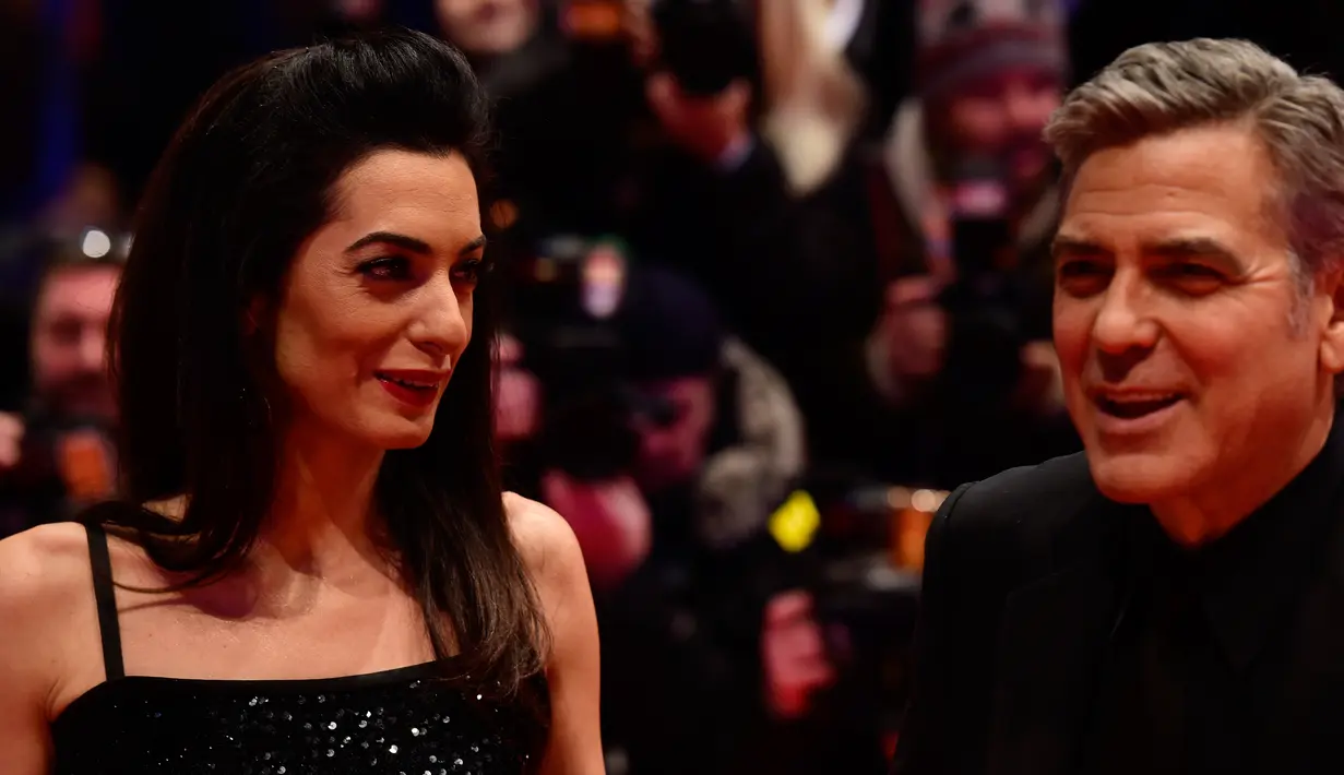 Amal Alamuddin tersenyum sambil menatap suaminya yang juga aktor AS, George Clooney saat tiba di karpet merah pemutaran film "Hail, Caesar!" pada pembukaan Berlin International Film Festival ke-66 di Berlin, Jerman, Kamis (11/2). (John MACDOUGALL/AFP)