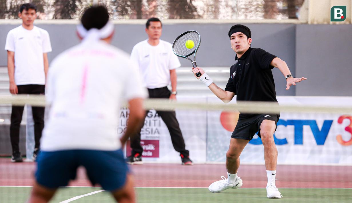 Selebritas Indonesia, Deddy Mahendra Desta berusaha mengembalikan bola ke arah pasangan Rezky Aditya dan Tanta Ginting pada laga tenis nomor ganda putra Turnamen Olahraga Selebriti Indonesia di GOR UNJ, Jakarta, Minggu (30/07/2023). Desta yang berpasangan dengan Raffi Ahmad menang dengan skor 4-6, 6-4, dan 6-4. (Bola.com/Bagaskara Lazuardi)