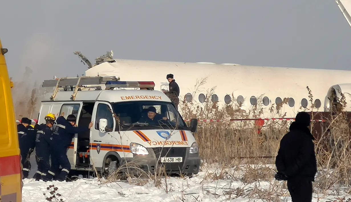 Polisi berjaga saat petugas penyelamat mengevakuasi korban jatuhnya pesawat maskapai Bek Air di dekat Bandara Almaty, Kazakhstan, Jumat (27/12/2019). Pesawat Bek Air sedang dalam perjalanan dari Bandara Internasional Almaty menuju Nur-Sultan saat pesawat hilang kontak. (AP Photo/Vladimir Tretyakov)