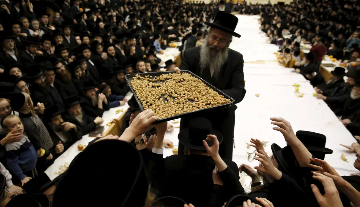 Pria Yahudi Ultra-Orthodoks dari dinasti Belz Hasidic membagikan kacang pada jemaat lainnya saat perayaah Tu Bishvat, hari Arbor Yahudi, Jerusalem, (25/1). Tu Bishvat dirayakan dengan menanam pohon dan makan buah dan kacang kering. (REUTERS/Baz Ratner)