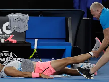 Petenis Spanyol, Rafael Nadal mendapat perawatan dari pelatihnya terkait cedera paha kanan pada perempat final Australia Terbuka 2018 di Melbourne, Selasa (23/1). Nadal mundur di set kelima saat menghadapi petenis Kroasia, Marin Cilic. (AP/Dita Alangkara)