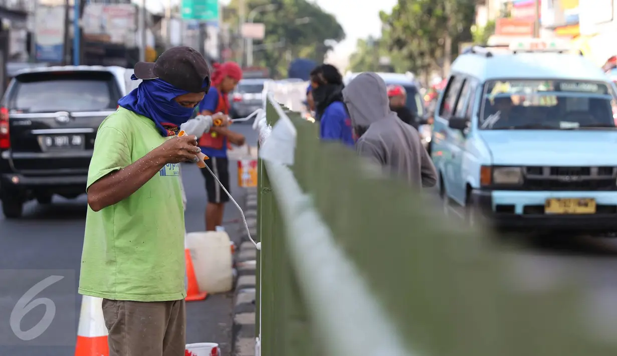 Sejumlah pekerja melakukan pengecatan pembatas jalan di kawasan Pasar Minggu, Jakarta Selatan, Rabu (26/10). Pengecatan dilakukan sebagai bentuk perawatan agar pagar pembatas tetap rapi dan tidak tampak kusam. (Liputan6.com/Immanuel Antonius)