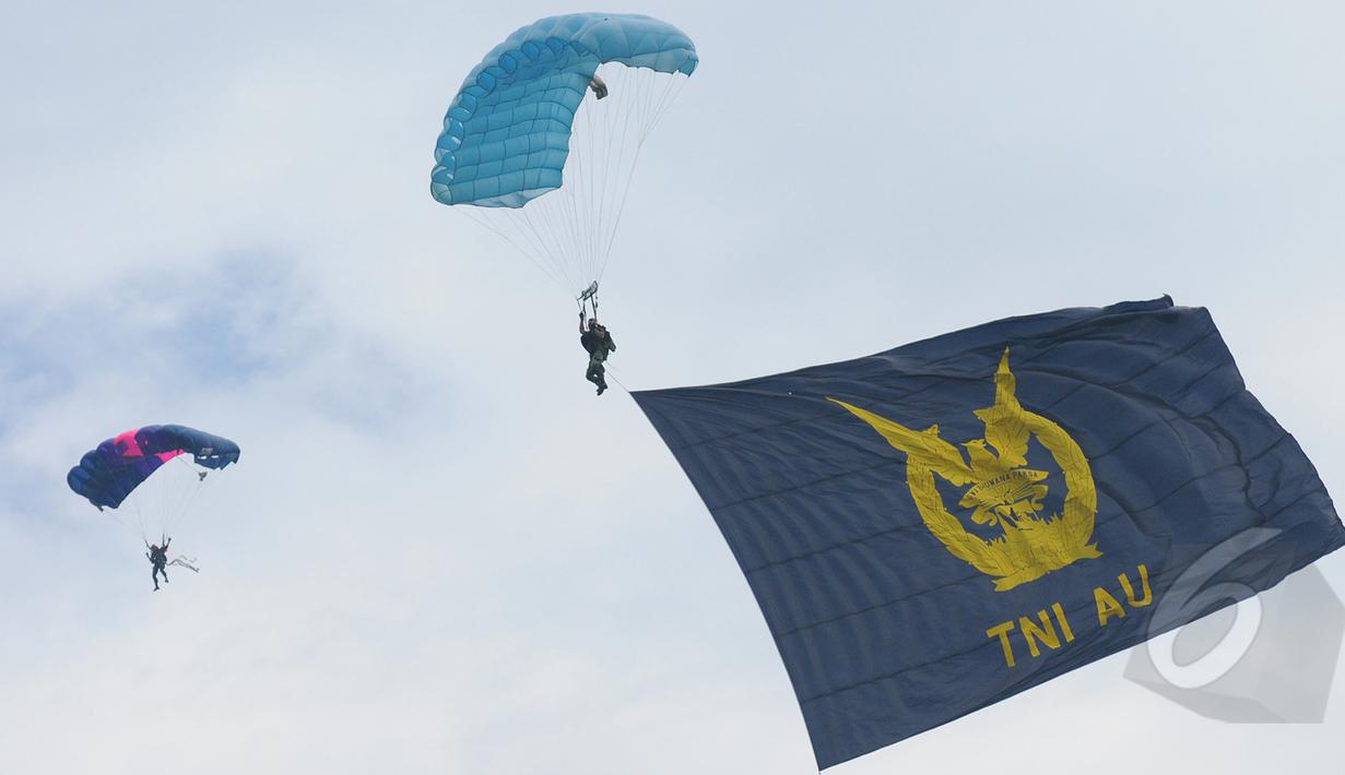 Aksi terjun payung prajurit TNI AU membawa saat peringatan HUT ke-69 TNI AU Tahun 2015 di Lanud Halim Perdanakusuma, Jakarta, Kamis (9/4/2015). Acara tersebut menampilkan demo darat dan atraksi udara. (Liputan6.com/Herman Zakharia)