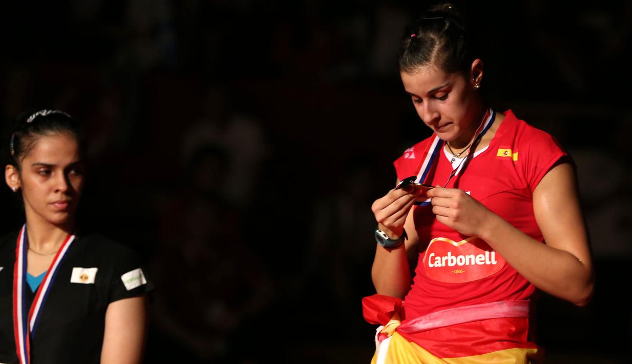 Carolina Marin memperhatikan medali emas yang diraihnya, sementara Saina Nehwal meliriknya. Minggu (16/8/2015). (Bola.com/Arief Bagus)