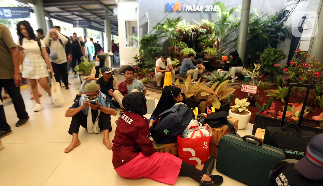 Calon pemudik yang akan menggunakan Kereta Api Jarak Jauh duduk di lantai menanti waktu keberangkatan di Stasiun Pasar Senen, Jakarta, Minggu (7/4/2024). (Liputan6.com/Helmi Fithriansyah)
