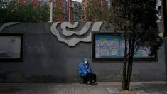 Seorang pekerja beristirahat di sepanjang dinding area perumahan yang di bawah perintah lockdown di Beijing, China, Senin (9/5/2022). Jutaan orang di Beijing tinggal di rumah pada 9 Mei 2022 ketika ibu kota China mencoba untuk menangkis virus corona Covid -19 dengan pembatasan ruang gerak. (Noel Celis / AFP )