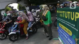 Petugas Satpol PP memberitahu warga terkait penutupan kawasan Kebun Binatang Ragunan, Jakarta, Minggu (16/5/2021). Sejumlah kawasan wisata di DKI Jakarta ditutup sementara untuk umum hingga 18 Mei 2021 untuk pemberlakukan penguatan protokol kesehatan COVID-19. (Liputan6.com/Helmi Fithriansyah)