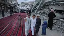 Para pemuda Palestina tertawa bersama saat para jemaah berkumpul di jalan yang rusak parah untuk melaksanakan salat menandai dimulainya Idul Adha, Hari Raya Kurban, di Khan Yunis, Jalur Gaza Selatan, pada Rabu 27 Mei 2026. (BASHAR TALEB/AFP)