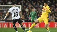 Bek Barcelona, Joao Cancelo, saat coba melewati gelandang Valencia, Diego Lopez, pada laga pekan ke-17 La Liga di Estadio Mestalla, Minggu (17/12/2023) dini hari WIB. Dalam duel tersebut, kedua tim harus puas bermain imbang 1-1. (AFP/Jose Jordan)