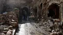 Dua orang pria melihat kondisi bangunan pasar lama di kota tua Aleppo, Suriah (18/1). Perang di Aleppo telah mereda lebih dari setahun yang lalu, namun kondisi bangunan di pasar ini masih belum pulih. (AP Photo/Hassan Ammar)