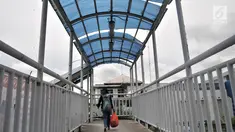 Pejalan kaki melintasi JPO yang tidak terawat di JPO Imigrasi Jakarta Timur, Kamis (17/1). JPO yang berada di depan Kantor Imigrasi Jakarta Timur dalam kondisi tidak terawat, seperti atap yang sudah rusak dan penuh coretan. (Merdeka.com/Iqbal S. Nugroho)