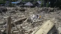 Warga desa memotong kayu-kayu yang hanyut oleh banjir bandang di Garoga, Provinsi Sumatera Utara, pada Kamis 4 Desember 2025. Banjir bandang di Desa Aek Garoga, Kecamatan Batang Toru, Tapanuli Selatan, Sumatera Utara, yang terjadi pada akhir November 2025 lalu membawa serta kayu-kayu gelondongan dalam jumlah besar. (YT HARIONO/AFP)