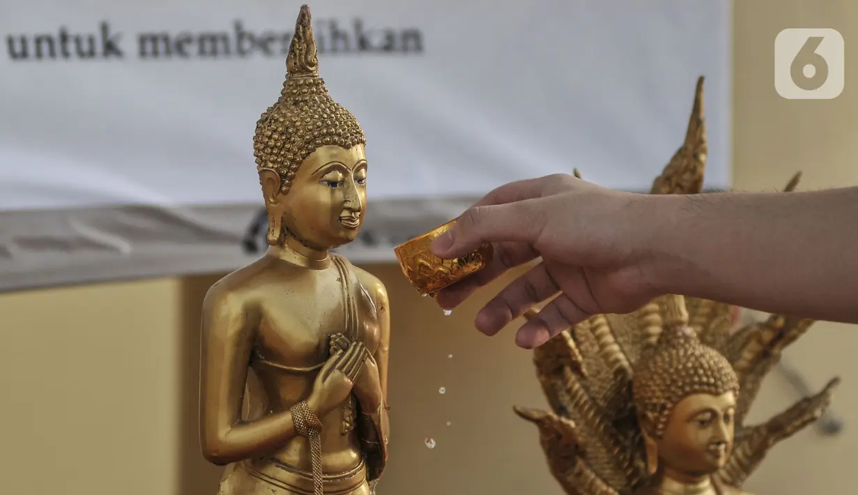 Jemaat menyiramkan air suci pada patung Buddha saat peringatan Tri Suci Waisak 2565 BE di Vihara Hemadhiro Mettavati, Cengkareng, Jakarta Barat, Rabu (26/5/2021). (merdeka.com/Iqbal S. Nugroho)
