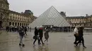 Orang-orang mengantre di depan Louvre Pyramide di Paris pada Minggu (1/3/2020). Louvre, museum yang paling banyak dikunjungi di dunia, ditutup sementara untuk pengunjung setelah para staf mengutarakan kecemasan dan ketakutannya tertular virus corona tipe baru, Covid-19. (Thomas SAMSON/AFP)