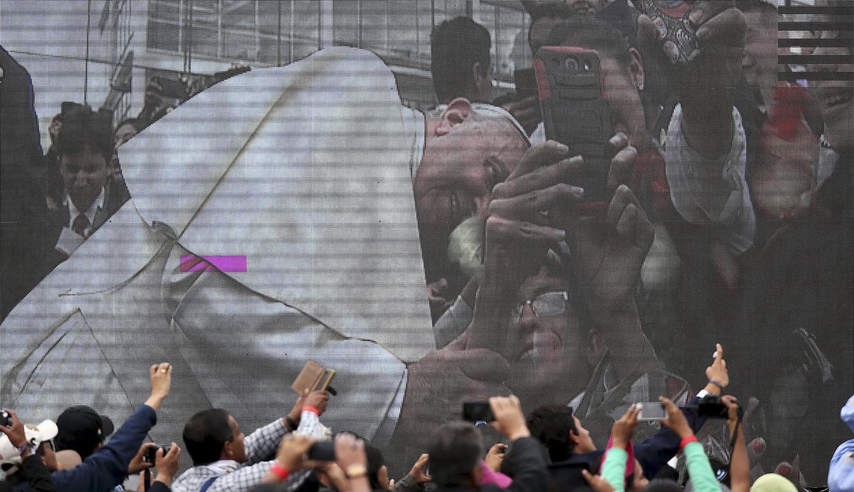 Paus Fransiskus tampak terlihat di layar besar saat tiba di Universitas Katolik, Quito,Ekuador,(7/ 7/2015). Tampak ribuan warga memadati lokasi lawatan Paus Fransiskus ke Ekuador . (REUTERS/Alessandro Bianchi)