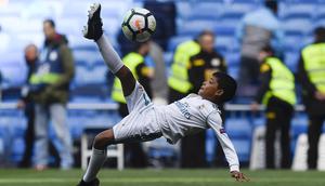 Putra dari Cristiano Ronaldo melakukan tendangan salto saat menemani sang ayah di Stadion Santiago Bernabeu, Madrid, Minggu (8/4/2018). Tendangan ini mirip seperti saat CR 7 membobol gawang Juventus. (AFP/Gabriel Bouys).