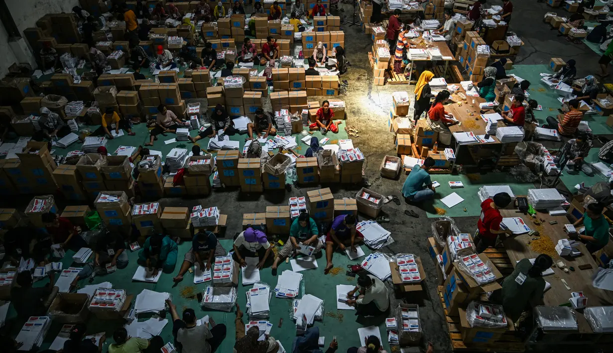 Sejumlah pekerja menyortir dan melipat surat suara untuk Pemilihan Umum (Pemilu) yang dijadwalkan digelar pada 14 Februari 2024 mendatang, di gudang KPU Surabaya, Jawa Timur, Kamis (21/12/2023). (Photo by Juni Kriswanto / AFP)