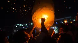 Para peserta melepaskan lentera ke udara selama Festival Tazaungdaing di Taunggyi, Myanmar pada 14 November 2018. Perayaan festival ini digelar saat bulan purnama bersinar di langit malam Myanmar. (Ye Aung THU / AFP)