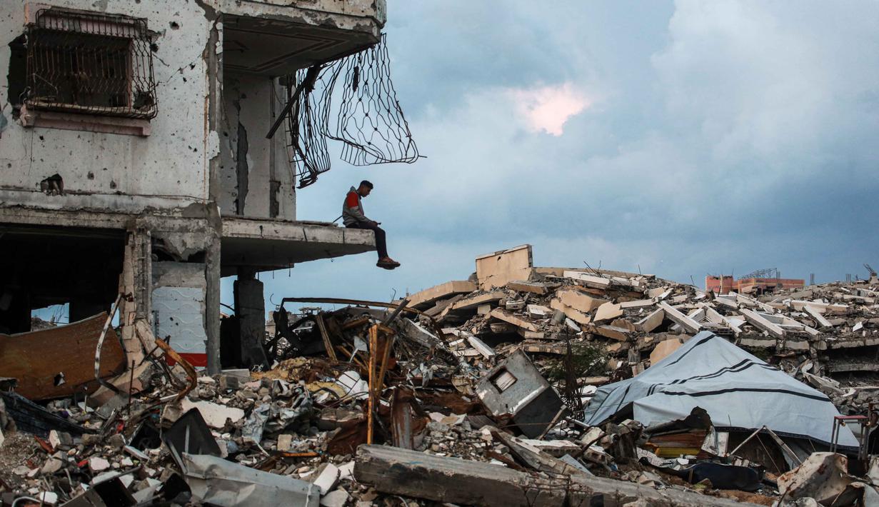 Seorang pria duduk di tepi reruntuhan bangunan di lingkungan Al-Saftawi, sebelah barat kota Jabalia, Jalur Gaza utara pada Rabu 10 Desember 2025. Secara keseluruhan, Kota Jabalia, termasuk lingkungan Al-Saftawi, digambarkan sebagai kota hantu. (BASHAR TALEB/AFP)