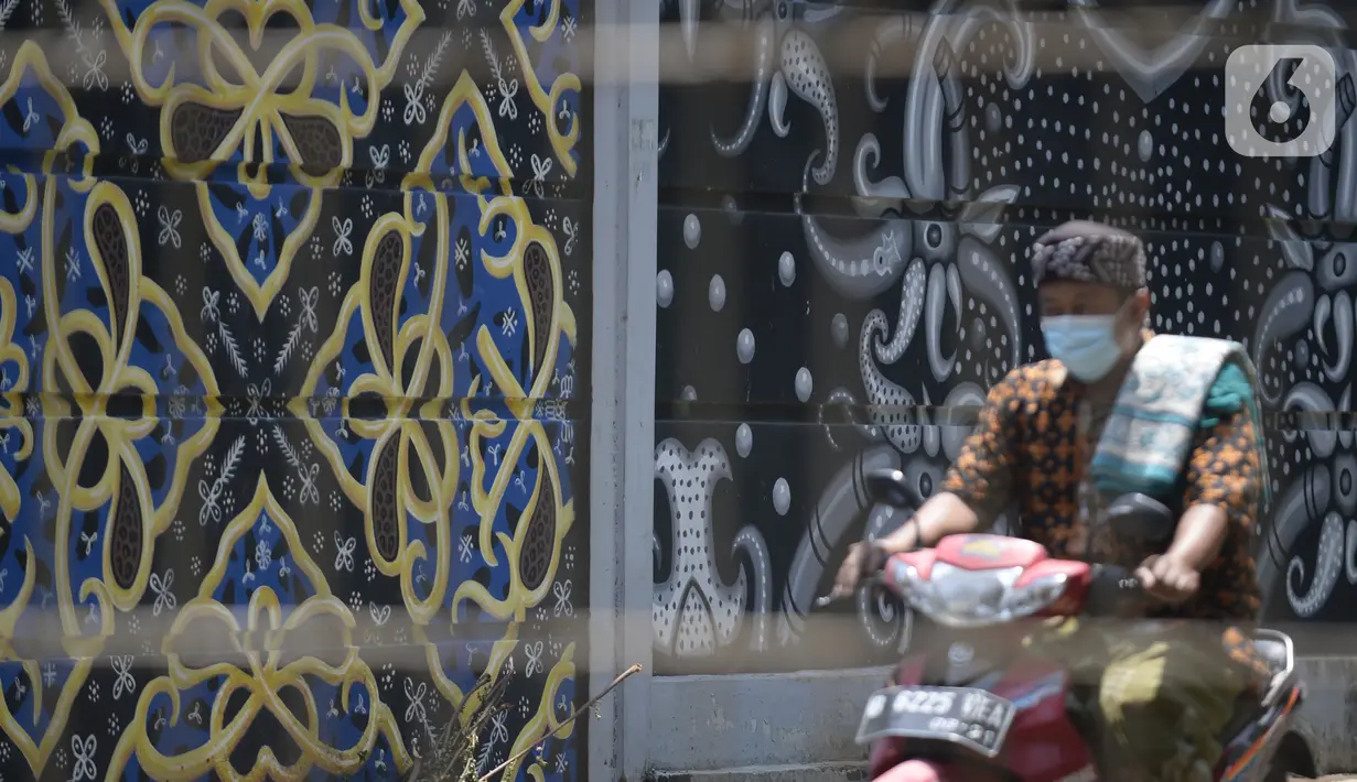 Pengendara sepeda motor melewati mural batik kembang mayang di Kampung Batik, Kelurahan Larangan Selatan, Kota Tangerang, Banten, Rabu (26/8/2020). Di tempat yang menjadi destinasi wisata tersebut kita bisa melihat langsung pembuatan dan mengikuti pelatihan membatik. (merdeka.com/Dwi Narwoko)