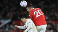 Bek Manchester United (MU) Diogo Dalot (kanan) berebut bola dengan striker Tottenham Hotspur Son Heung-Min (kiri) pada pekan ke-29 Liga Inggris di Old Trafford, Minggu (13/3/2022) dini hari WIB. Ronaldo mencetak hattrick untuk membawa MU menang 3-2 atas Tottenham. (Lindsey Parnaby/AFP)