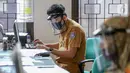Petugas loket lengkap dengan masker dan face shield sedang mengetik saat proses pembuatan KTP Elektronik di Kecamatan Pamulang, Tangerang Selatan, Senin (15/6/2020). Dukcapil Tangsel membuka layanan rekaman E-KTP jelang Pilkada dengan menerapkan ketentuan New Normal. (Liputan6.com/Fery Pradolo)