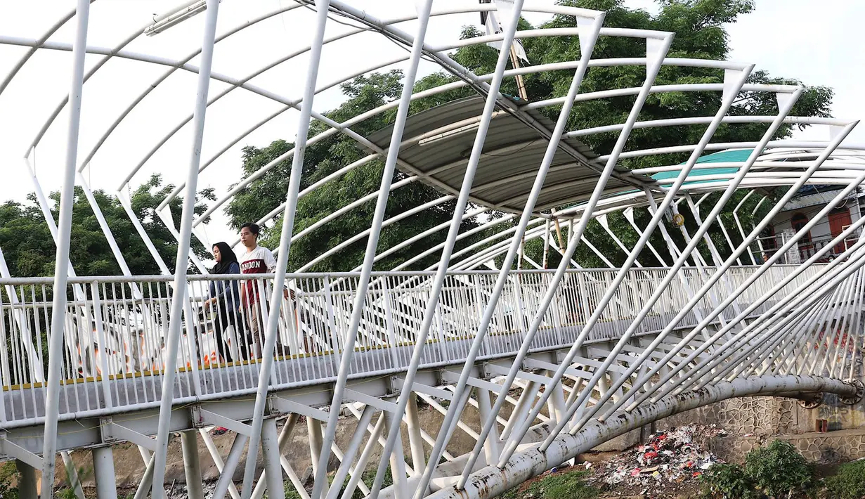 Pejalan kaki melintasi jembatan penyeberangan orang (JPO) Jayakarta yang atapnya rusak dan hilang di Menteng, Jakarta, Jumat (11/1). Kondisi atap JPO yang rusak akibat tertiup angin mengganggu kenyamanan pejalan kaki. (Liputan6.com/Immanuel Antonius)