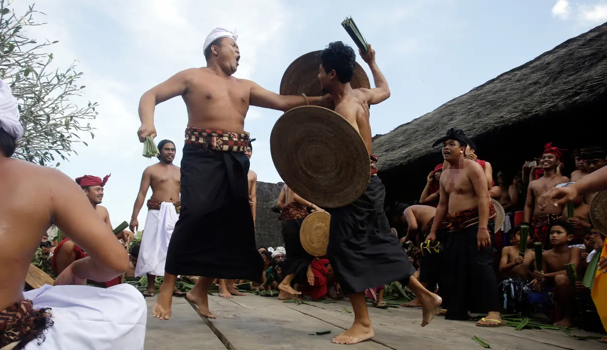 Dua orang laki-laki saling serang saat mengikuti Perang Pandan di Bali (8/6). Tradisi ini merupakan rangkaian upacara keagamaan yang dilakukan ketika upacara Sasih Sembah digelar. (AP/Firdia Lisnawati)