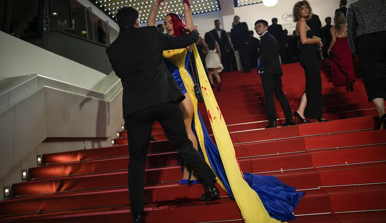 Dalam sebuah aksi nyata untuk mendukung negara yang dilanda perang tersebut, perempuan muda tak dikenal itu menyiram dirinya dengan zat berwarna merah di pemutaran perdana film 'Acide' karya Just Philippot. (AP Photo/Daniel Cole)