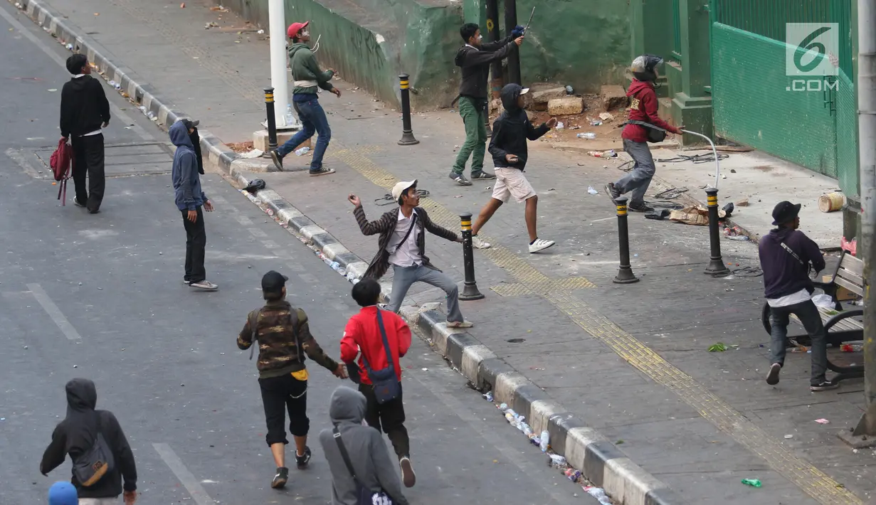 Pelajar melempari Gedung DPR dengan batu saat berunjuk rasa di Palmerah, Jakarta, Rabu (25/9/2019). Pihak kepolisian menembakan gas air mata untuk memukul mundur pelajar. (Liputan6.com/Angga Yuniar)
