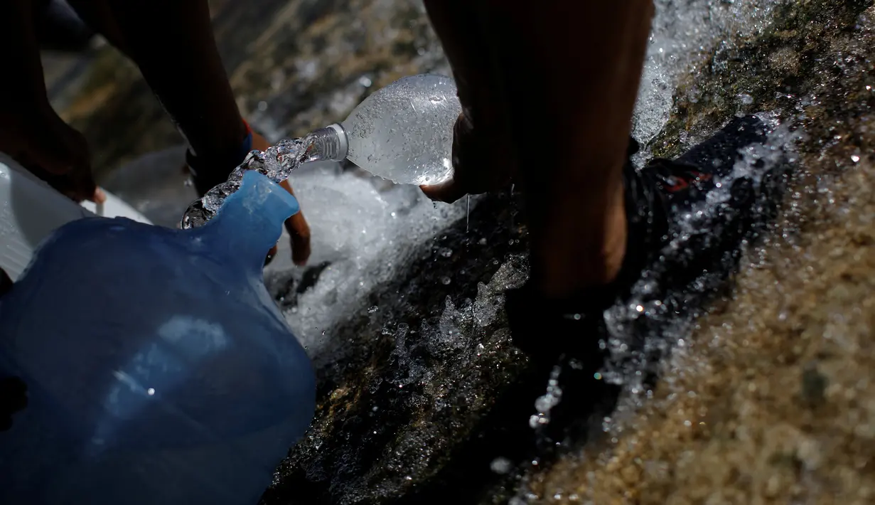 Warga mengumpulkan air yang keluar melalui saluran pembuangan air limbah yang mengalir ke Sungai Guaire di Caracas, 11 Maret 2019. Pemadaman listrik selama berhari-hari di Venezuela berdampak terhadap krisis air. (REUTERS/Carlos Garcia Rawlins)