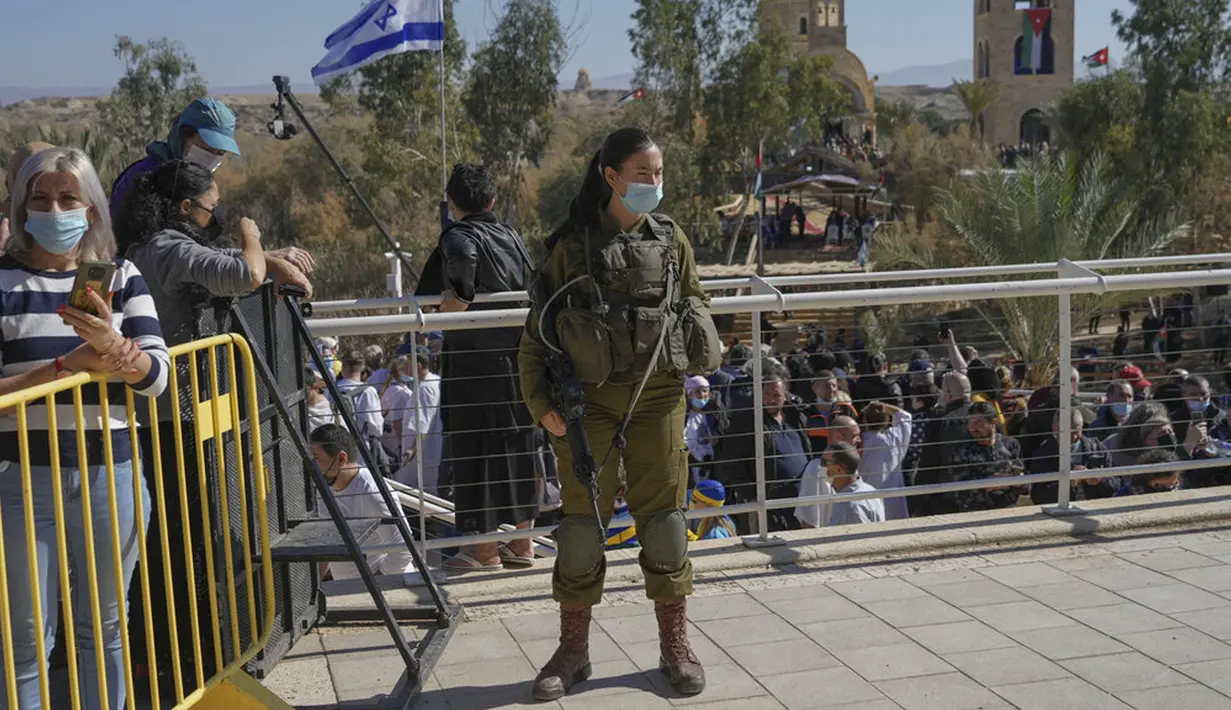 Seorang tentara Israel berjaga saat upacara pembaptisan pada perayaan Epiphany umat Kristen Ortodoks di Qasr el Yahud, dekat kota Yerikho, Tepi Barat, 18 Januari 2022. Sungai Yordan dipercaya menjadi tempat di mana Yesus dibaptis. (AP Photo/Mahmoud Illean)