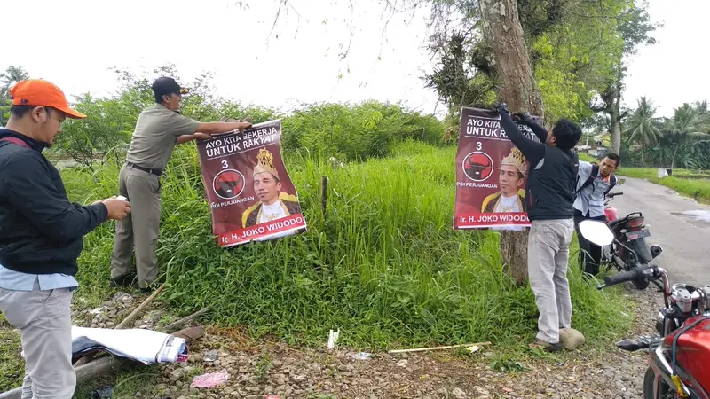 Petugas mencopot APK yang melanggar aturan pemasangan. Di antaranya, poster Jokowi bermahkota alias Jokowi raja. (Liputan6.com/Panwas Banyumas/Muhamad Ridlo)