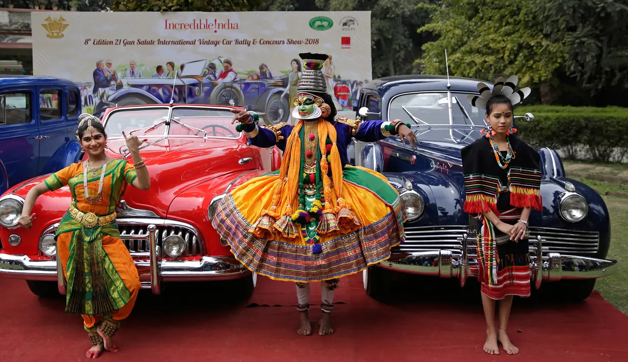 Penari berpose dengan mobil vintage yang baru direstorasi dalam pameran 21 Gun Salute Heritage and Cultural Trust di New Delhi, India, Selasa (6/2). Lebih dari 100 mobil vintage dan klasik akan berpartisipasi di reli tahunan. (AP Photo/Altaf Qadri)