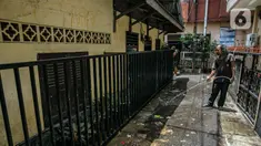 Warga membersihkan jalan usai terendam banjir di permukiman kawasan Kampung Melayu, Jakarta, Selasa (9/2/2021). Banjir yang berangsur surut dimanfaatkan warga untuk membersihkan rumah dan barang-barang dari endapan lumpur. (Liputan6.com/Faizal Fanani)