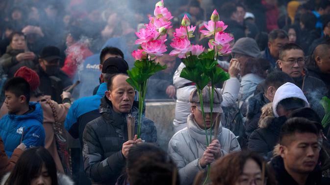 Warga memegang karangan bunga dan dupa ketika mereka berdoa di Kuil Lama di Beijing (5/2). Orang-orang China merayakan hari pertama Tahun Baru Imlek pada hari Selasa, Tahun Babi di zodiak Tiongkok dengan berdoa di kuil. (AP Photo/Mark Schiefelbein)