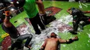 Pemain gulat yang dikenal Ciclope (tengah) terkapar di dalam ring setelah berhasil dibantai oleh lawannya, Los Malkriados dalam pertandingan gulat ekstrim di Arena Neza di pinggiran Mexico City, Meksiko (28/10). (Reuters/ Carlos Jasso)