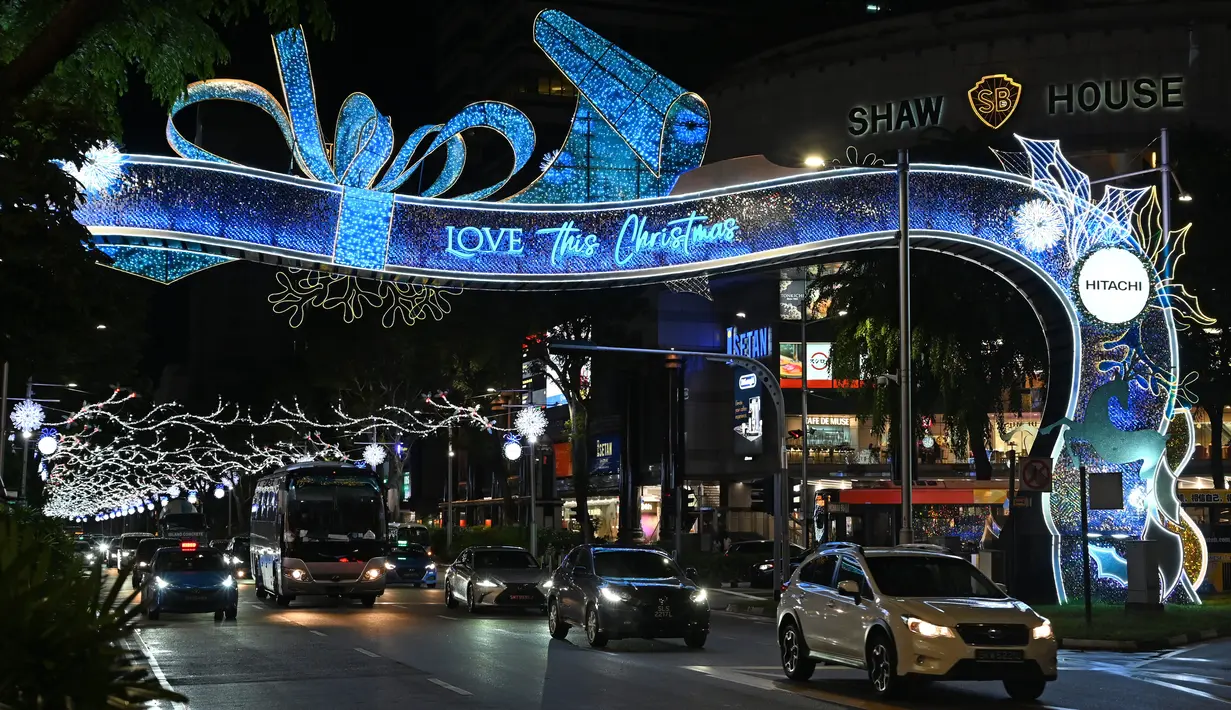 Kendaraan melintas di sepanjang distrik perbelanjaan utama Singapura di Orchard Road yang dihiasi lampu Natal pada Selasa (8/12/2020). Mengusung tema Love This Christmas, acara tahun ini lebih sunyi karena aktivitas jalanan dibatasi di tengah pandemi Covid-19. (ROSLAN RAHMAN / AFP)