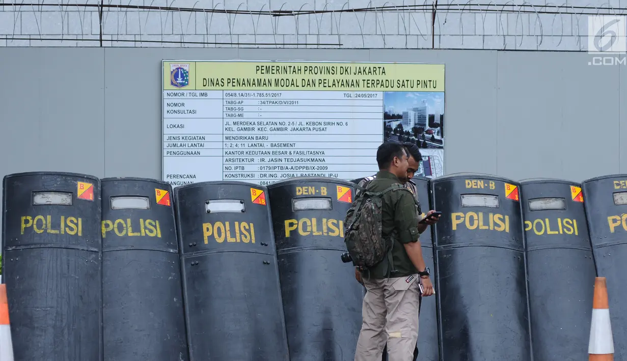 Petugas berdiri di depan tameng polisi saat menjaga aksi dukungan bagi Palestina di depan Kedubes AS, Jakarta, Minggu (10/12). Mereka memprotes keputusan Presiden Trump yang mengakui Yerusalem jadi Ibu Kota Israel. (Liputan6.com/Helmi Fithriansyah)