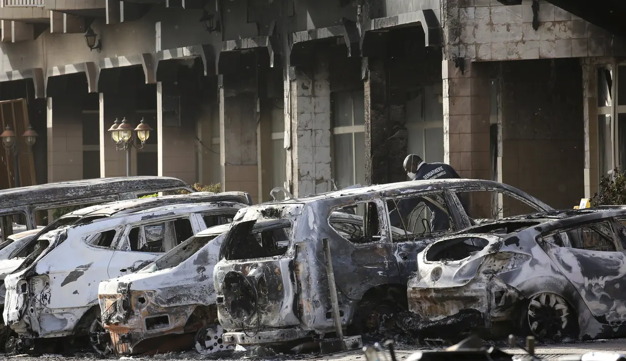Petugas kepolisian memeriksa mobil yang hangus terbakar pasca teror di luar hotel Splendid, Ouagadougou , Burkina Faso, (16/1). Petugas berhasil merebut kembali lokasi dimana beberpa kelompok al Qaeda menyandera beberapa orang. (REUTERS / Joe Penney)
