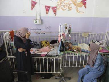 Amira Al-Jojo (kiri) berdiri di samping putranya yang berusia 10 bulan, Yousef Al-Jojo, yang menderita kekurangan gizi di Rumah Sakit Martir Al-Aqsa, tempat ia menjalani perawatan, di Deir al-Balah di Jalur Gaza tengah pada Sabtu, 1 Juni 2024. (AP Photo/ Jehad Alshrafi)