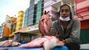 Penjual menunjukkan ikan dagangannya di sebuah pasar tradisional usai gempa dan tsunami melanda Palu, Sulawesi Tengah, Kamis (4/10). Banyak warga berdatangan untuk berbelanja saat pasar mulai buka. (Permata SAMAD/AFP)