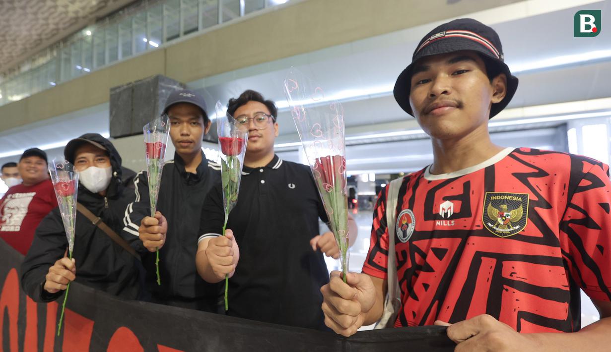 Suporter menunjukkan bunga yang akan diberikan kepada para pemain Timnas Futsal Indonesia yang tiba di Bandara Soekarno-Hatta, Tangerang, Senin (11/11/2024). (Bola.com/M Iqbal Ichsan)